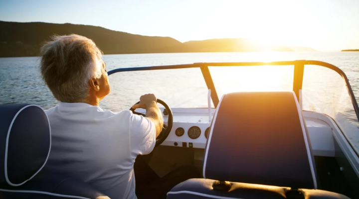 Man driving boat into a sunset